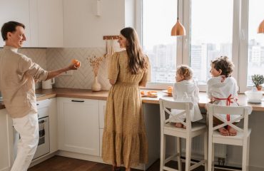 A family having fun preparing breakfast in a cozy kitchen with a city view.